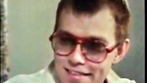 Vintage retro punk guy with mohawk haircut and red aviator sunglasses smirking close-up