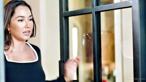 Karlee Grey in black top by glass door, seductive gaze