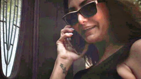 Naughty brunette babe with huge tits and deep cleavage talking on phone in sunglasses