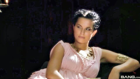 Curly-haired brunette in seductive Roman pink gown and gold jewelry