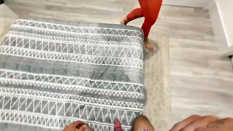 POV hand caressing barefoot woman's red-painted toes and legs in tight red leggings on bed