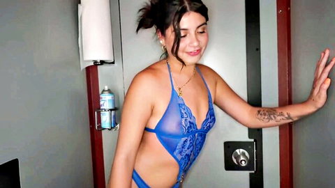 Luna in sheer blue lingerie, smiling seductively in gloryhole setup