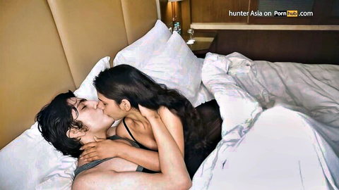 Asian couple passionately kissing in bed, lingerie tease