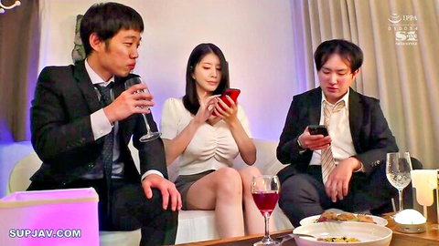 Two suited men and sexy Asian woman in blouse and short skirt sipping wine while checking phones on couch