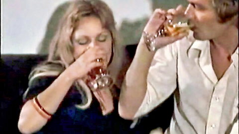 Vintage blonde woman and shaggy haired man intimately sipping whiskey together