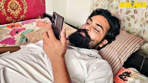 Bearded Desi husband lounging on bed in white shirt, eyeing spicy feet fetish with hot Bhabhi