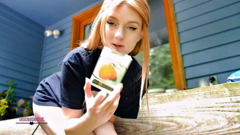Redhead teen squats upskirt on porch holding juice carton teasing pussy