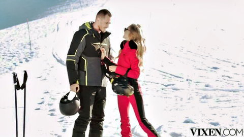 Blonde ski babe in pink outfit flirts closely with handsome guy on snowy mountain slopes