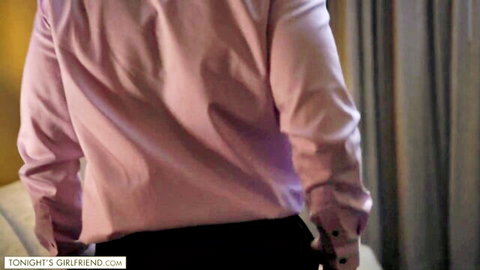 Man in pink shirt and black pants standing by couch from behind