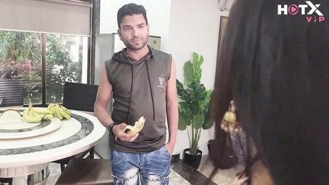 Desi Indian man in tank top holds banana teasingly near long-haired woman