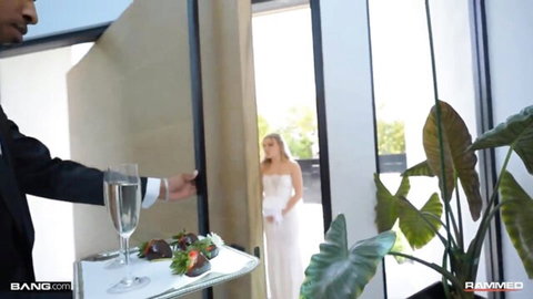 Tuxedo groom offers champagne and strawberries to sexy blonde bride in white wedding gown