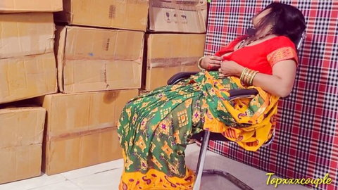 Seductive Indian MILF in green saree lounging back in chair amid warehouse boxes