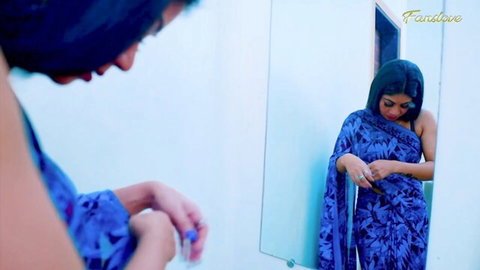 Desi bhabhi in blue saree teasingly adjusts fabric, exposing midriff