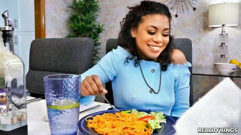Jeni Angel, black beauty in blue top, smiling while eating pasta before interracial fun