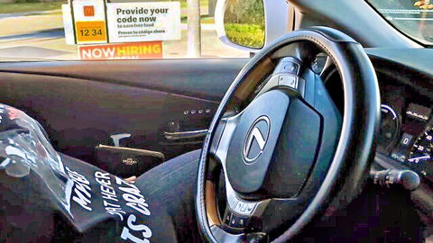 Woman's denim-clad legs spread wide on car seat inside Lexus near NOW HIRING sign outside window