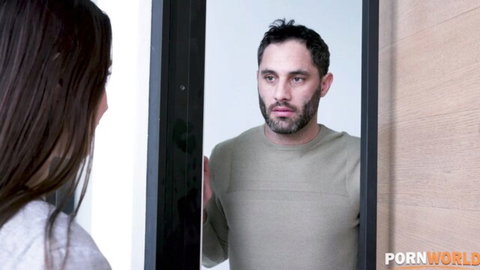 Brunette with long hair in tight top stares into mirror at bearded man's reflection