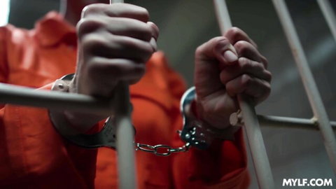 Skylar Snow in orange prison jumpsuit, handcuffed gripping cell bars