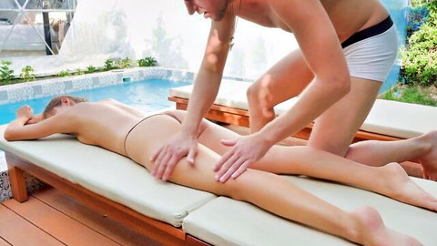Muscular guy in briefs gropes and massages busty blonde's bare ass cheeks poolside