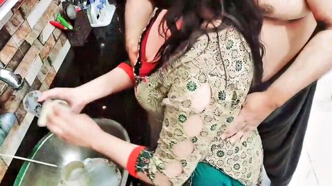 Indian woman in saree washing dishes while shirtless man gropes her hips from behind in kitchen