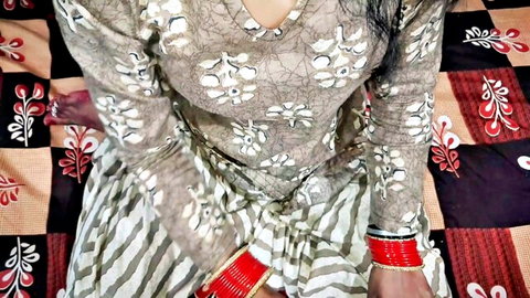 Young Indian Bhabhi in patterned dress posing seductively on bed