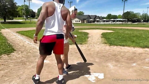 Muscular black stud in tight red shorts and blonde babe in matching outfit strut on baseball field