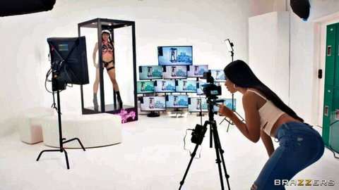 Ebony babe in tight jeans and crop top photographs lingerie model posing in glass cage on Brazzers set