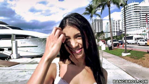 Young tanned Latina with small tits and long hair smiling shielding eyes near Miami yacht