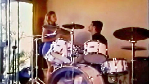 Blonde babe in short blue mini dress bends over drums teasing drummer in vintage retro scene