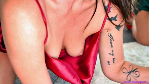 Tattooed brunette in red satin lingerie with deep cleavage