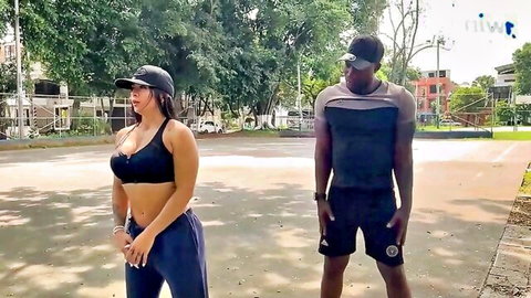 Silvana Lee in sports bra and sweatpants with muscular black man outdoors