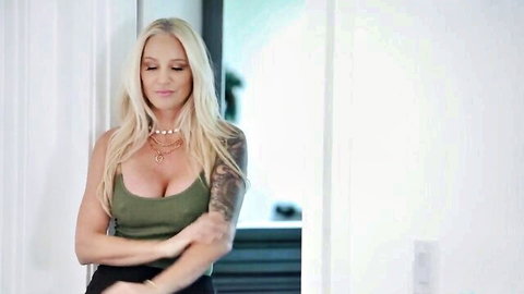 Blonde MILF Alexis Malone in low-cut green top, showing deep cleavage and tattoos