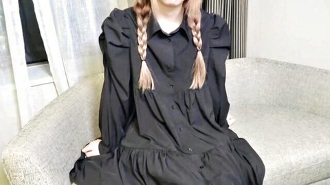 Cute East Asian girl with blonde pigtails smiling in black puffed-sleeve dress on couch