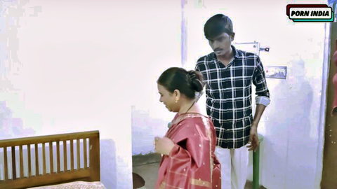 Mature Indian wife in red saree mops floor as young stranger stands close behind her