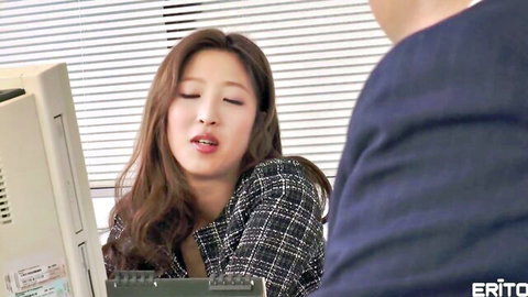 Boss leans close whispering to sexy Asian office employee at desk