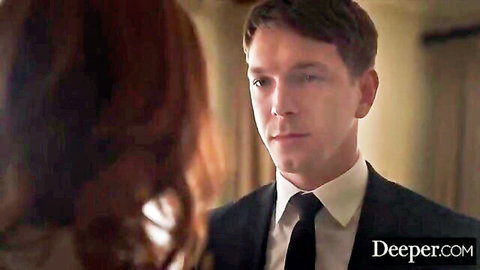 Suited man stares intensely at redhead woman's back in close teasing encounter
