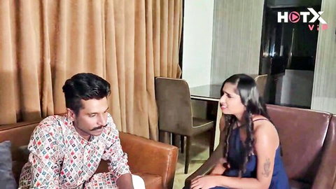 South Asian couple intimately talking on leather couch in bedroom