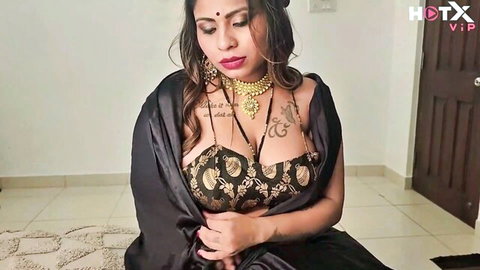 Seductive Indian Bhabhi in black saree blouse, teasing with curves and jewelry