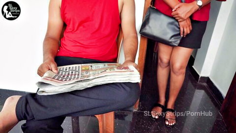 Sri Lankan woman in red blouse and black skirt teases man reading newspaper
