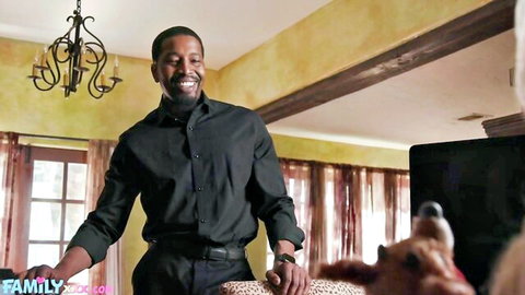 Smiling black man in black shirt pets small fluffy dog in luxurious living room