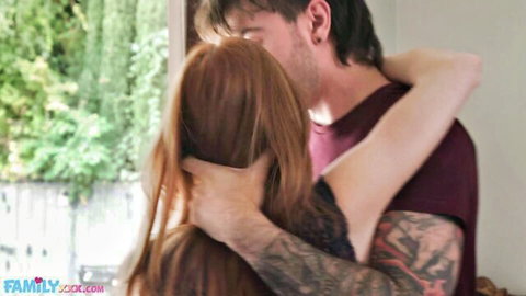 Redhead babe with long hair passionately kissing tattooed guy from behind in intimate embrace