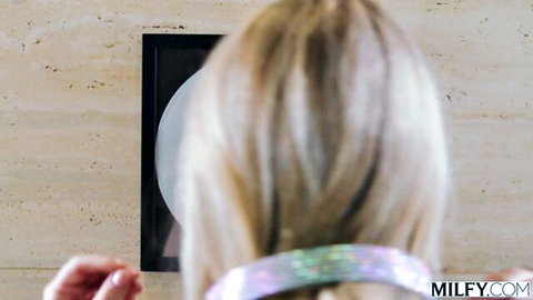 Blonde MILF with long hair reaches hand toward wall glory hole for cock