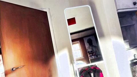 Empty bedroom with white mirror reflecting window and silhouette man, wooden door ajar and red backpack on floor