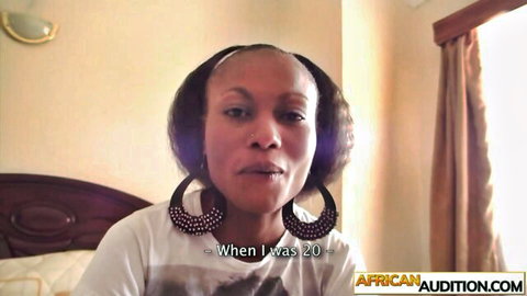 Ebony woman with big hoop earrings in white t-shirt on bed during African Audition casting interview