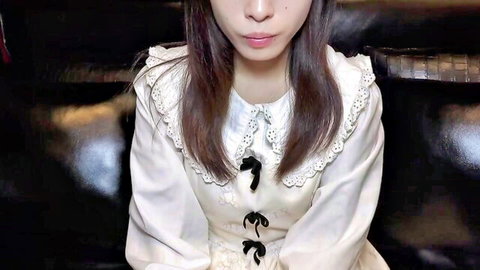 Cute Asian girl in lacy white dress with bows teasing on black couch