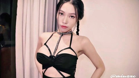 Seductive Asian babe in revealing black harness dress with braids and cleavage