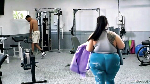 Thick BBW with massive jiggling ass in tight blue leggings walks in gym near muscular BBC stud