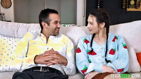 Cute brunette teen in strawberry sweater smiles with smiling boyfriend on couch