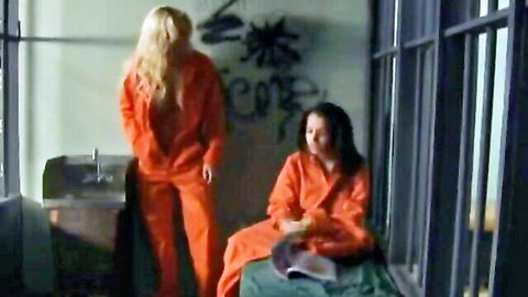 Shyla Stylez as sexy prison warden in orange jumpsuit with brunette inmate
