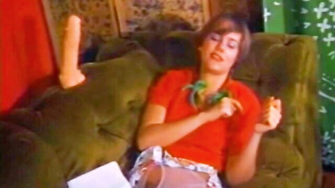 Vintage short-haired brunette spreads legs and fucks pussy with big dildo on green couch