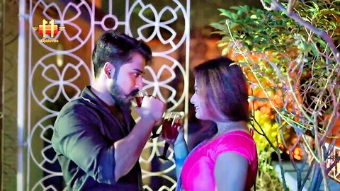Bearded Indian man feeds drink to woman in pink saree, romantic couple moment